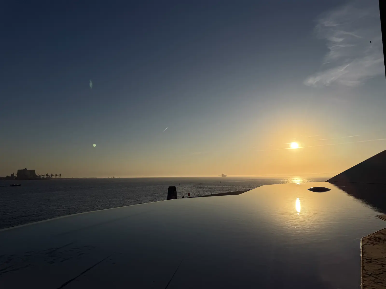 O sol baixo sobre o rio e o reflexo dele na água parada do espelho d'água.